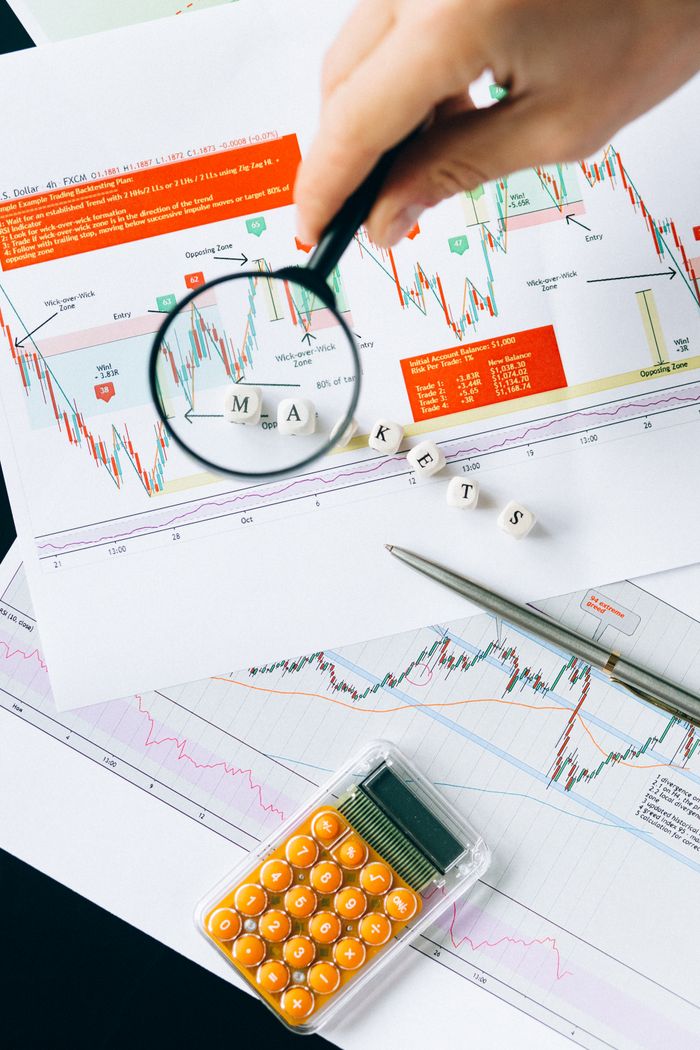 Services Magnifying glass focusing on market data and charts indicating financial analysis concept.